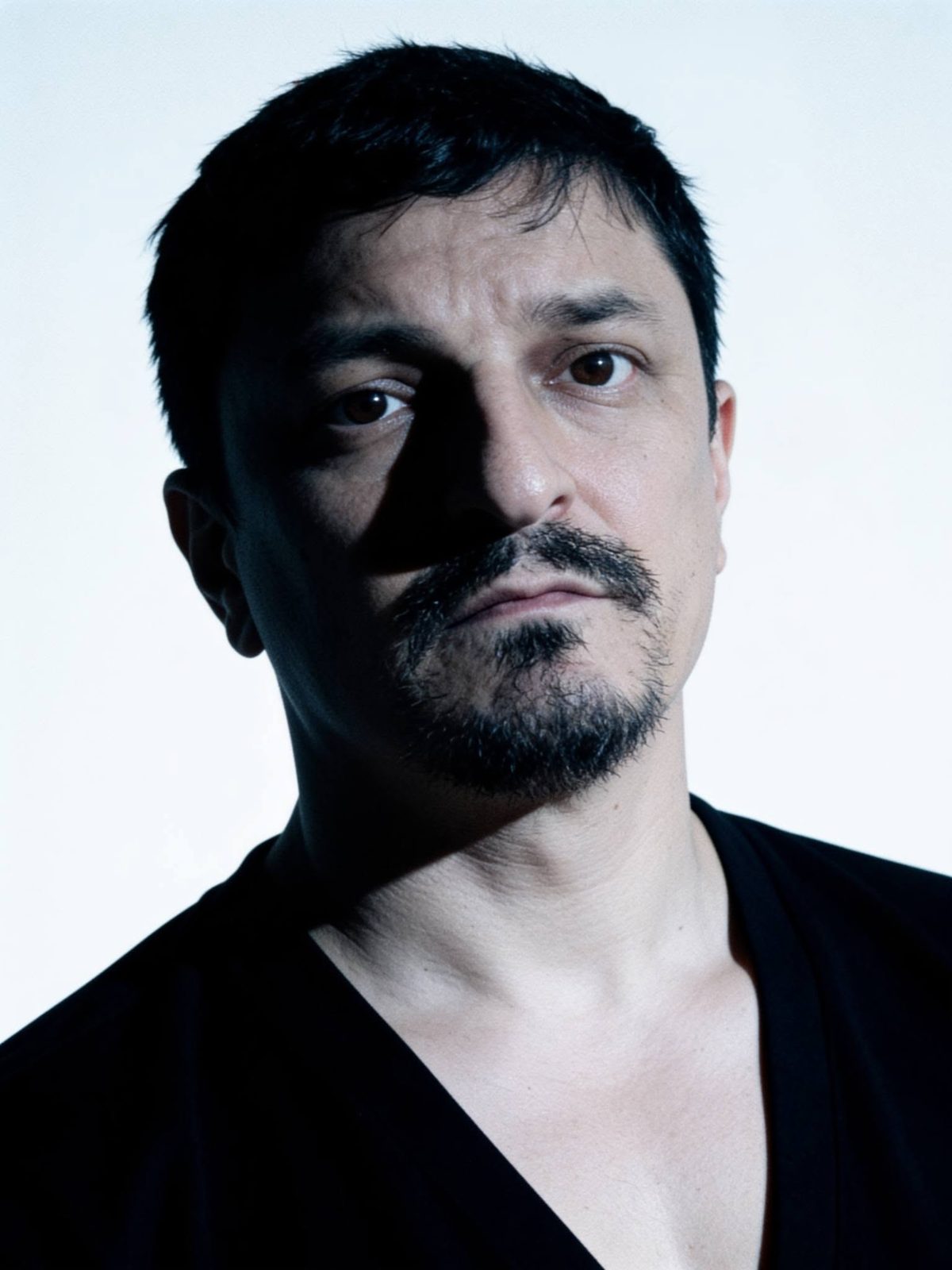 Kuya Manzano, founder of iChill Productions, dramatic portrait in a black V-neck on a white background