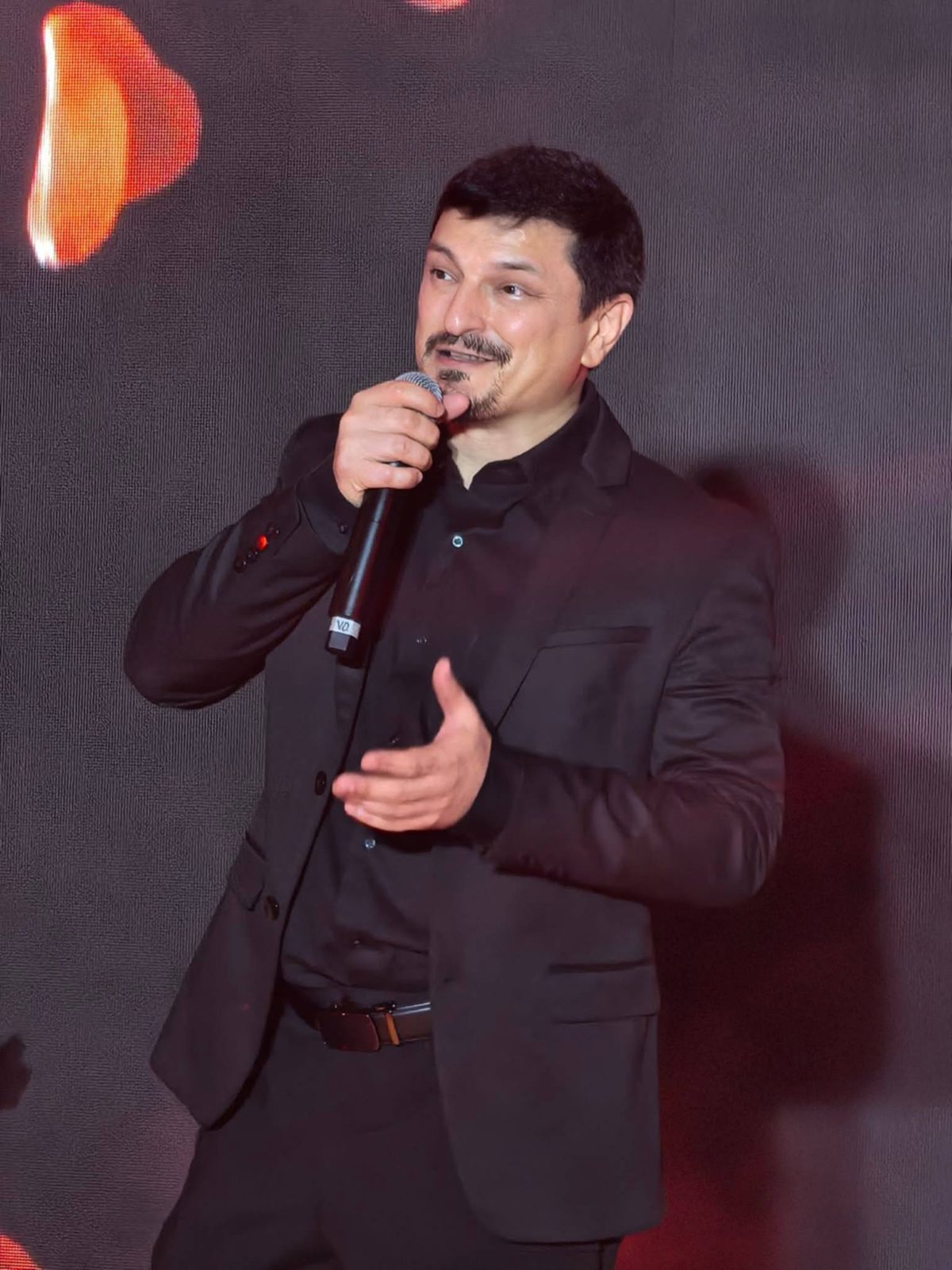 Kuya Manzano, founder of iChill Productions, on stage with a microphone in a black suit