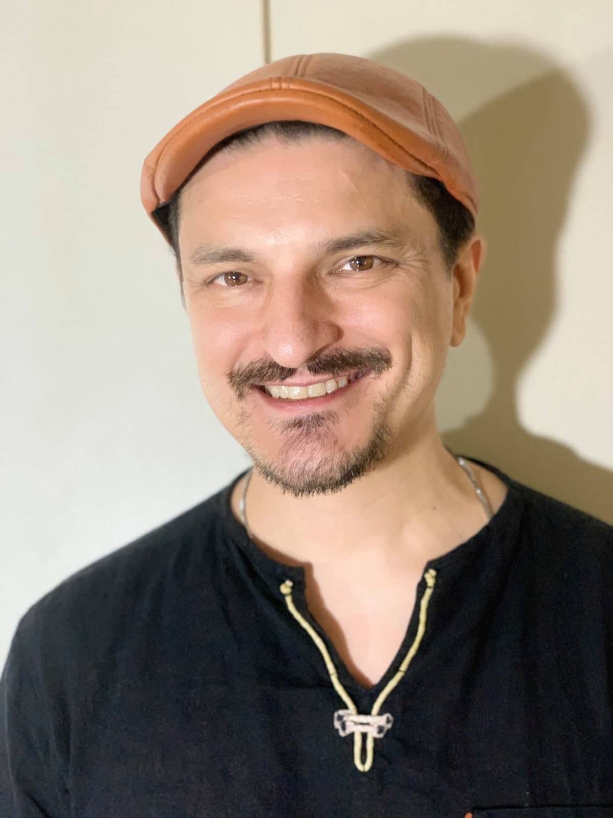 Kuya Manzano, founder of iChill Productions, smiling in a tan leather cap and black shirt